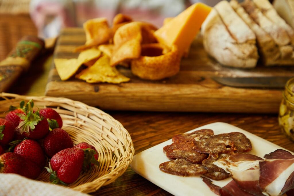 A delicious assortment of bread, cheese, cold cuts, and fresh strawberries on a wooden table.